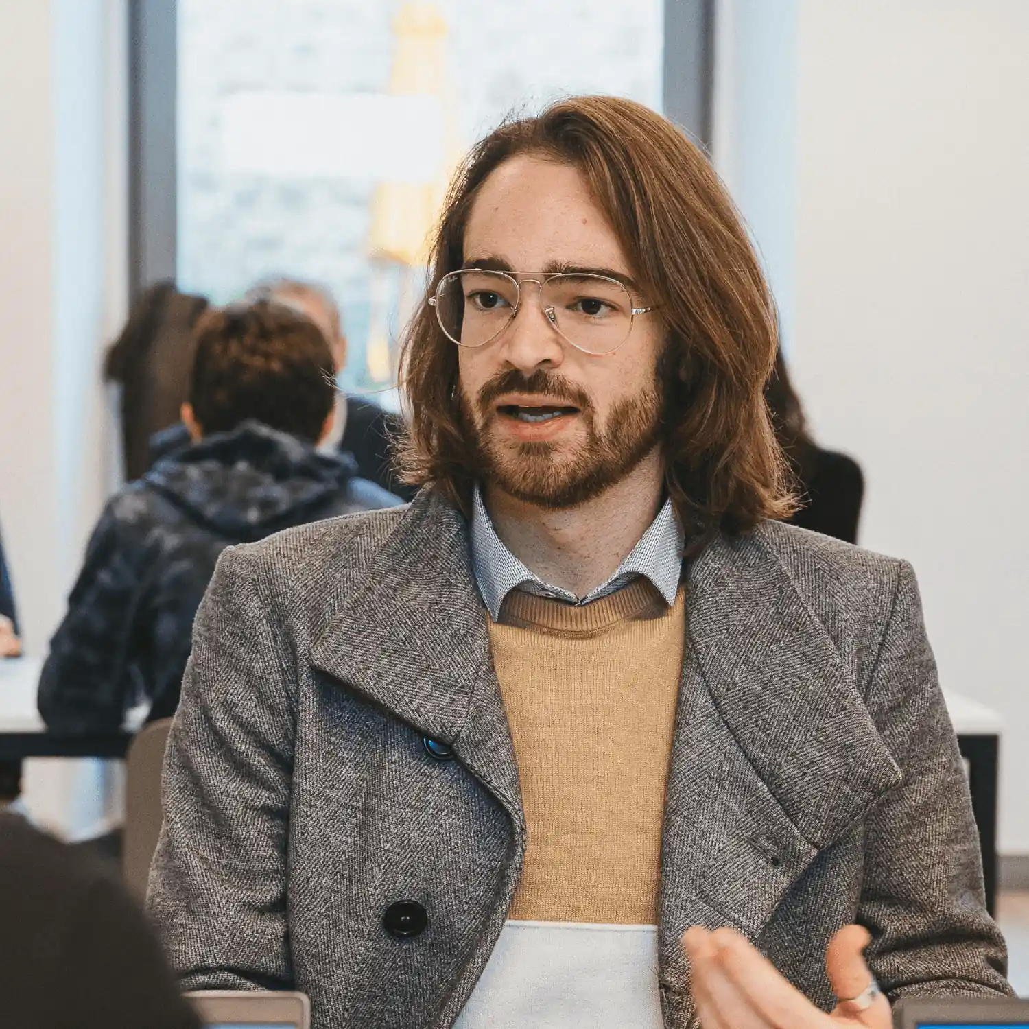 Uno studente di 42 Firenze con occhiali e capelli lunghi parla gesticolando, seduto in una sala.